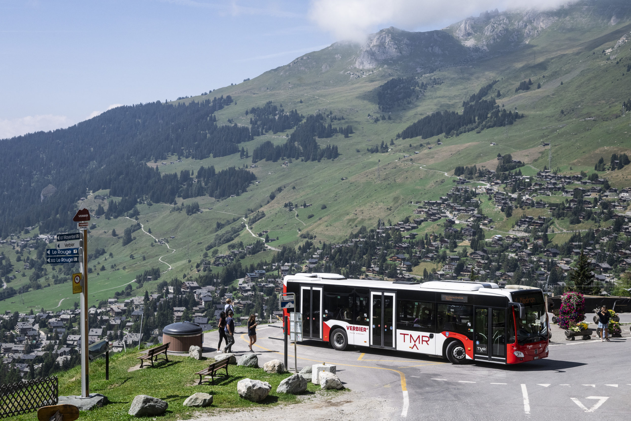 Bus TMR sur une route de montagne au milieu des prairies fleuries