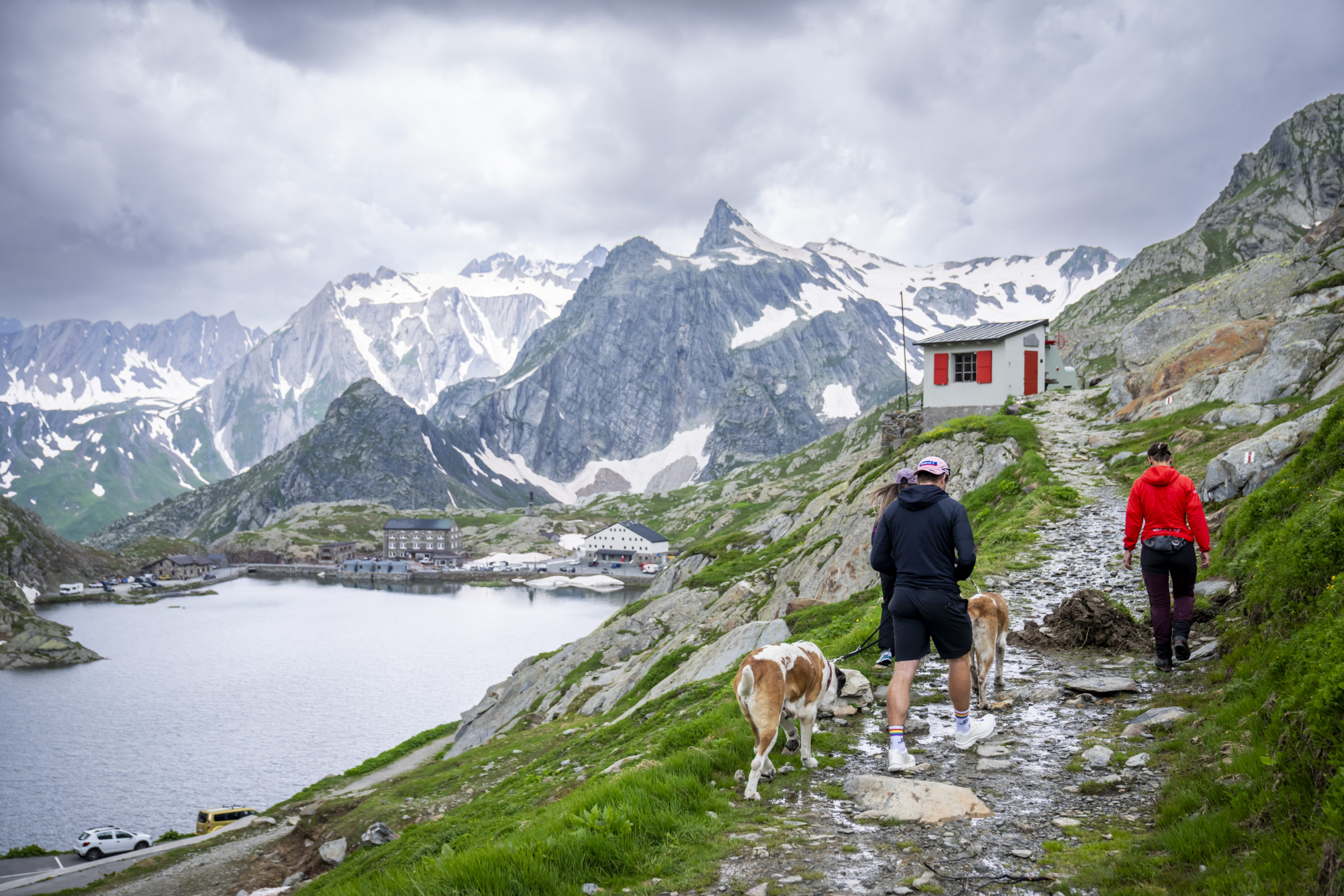 Randonneurs et leur chien devant un refuge de montagne dans les Alpes valaisannes