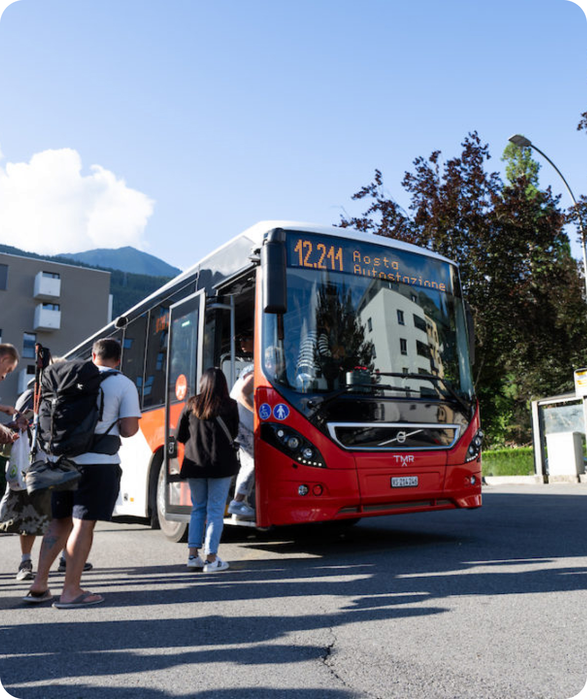 Voyageurs montant à bord d'un bus rouge TMR à un arrêt en Valais