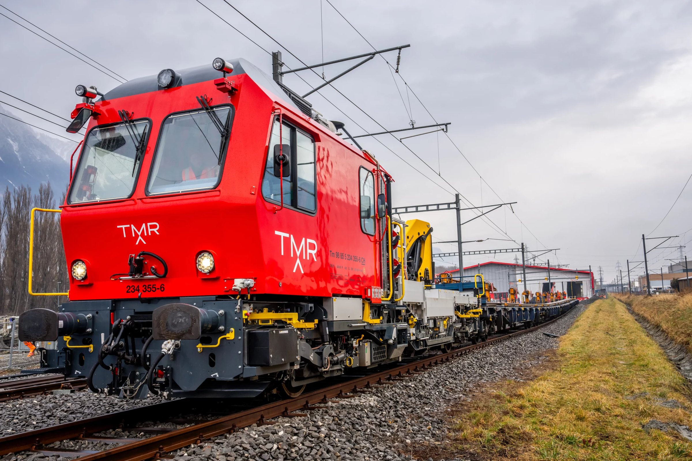 Véhicule d'entretien ferroviaire rouge aux couleurs TMR circulant sur les voies