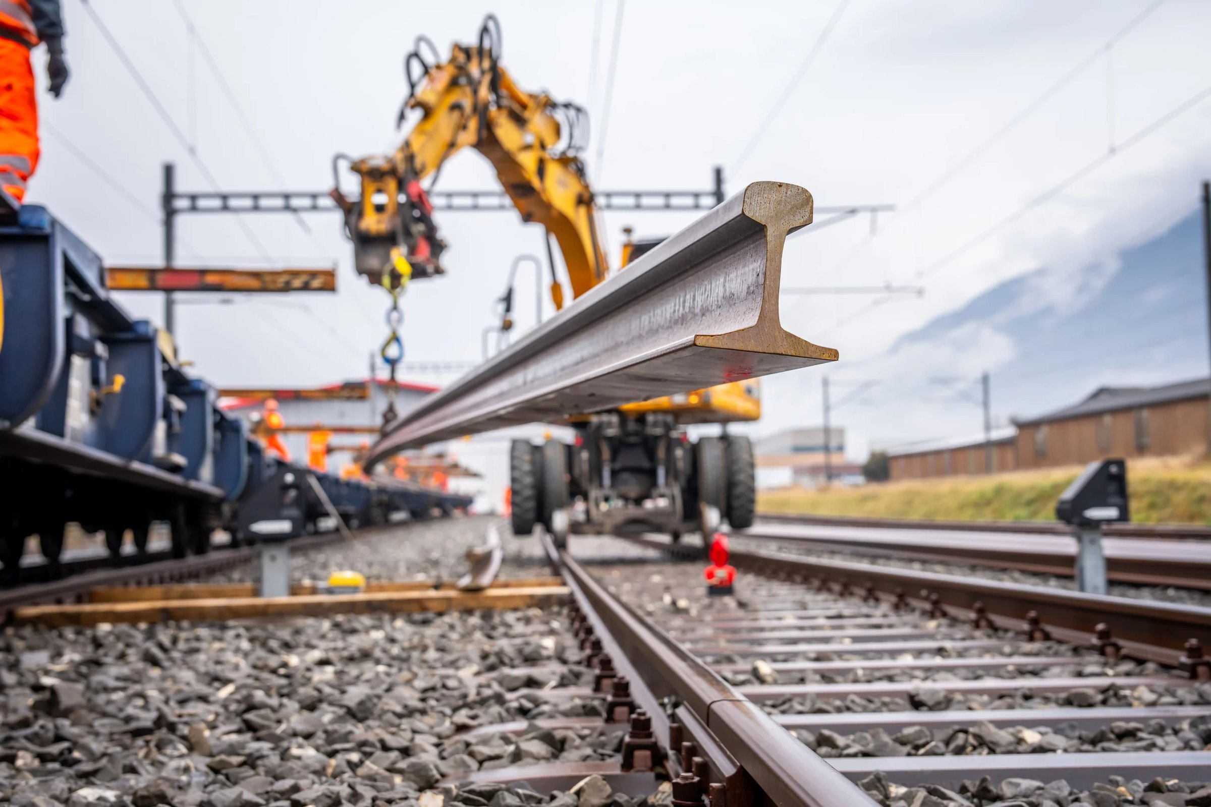 Pose d'un rail neuf à l'aide d'une grue rail-route sur une voie ferrée valaisanne