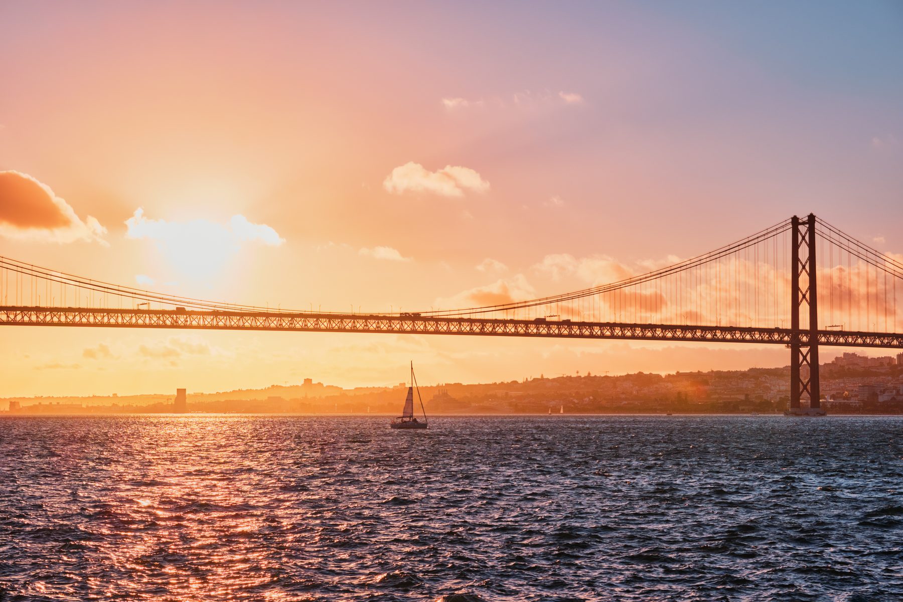 Ponte 25 de Abril in Lissabon bei Sonnenuntergang mit einem Segelboot