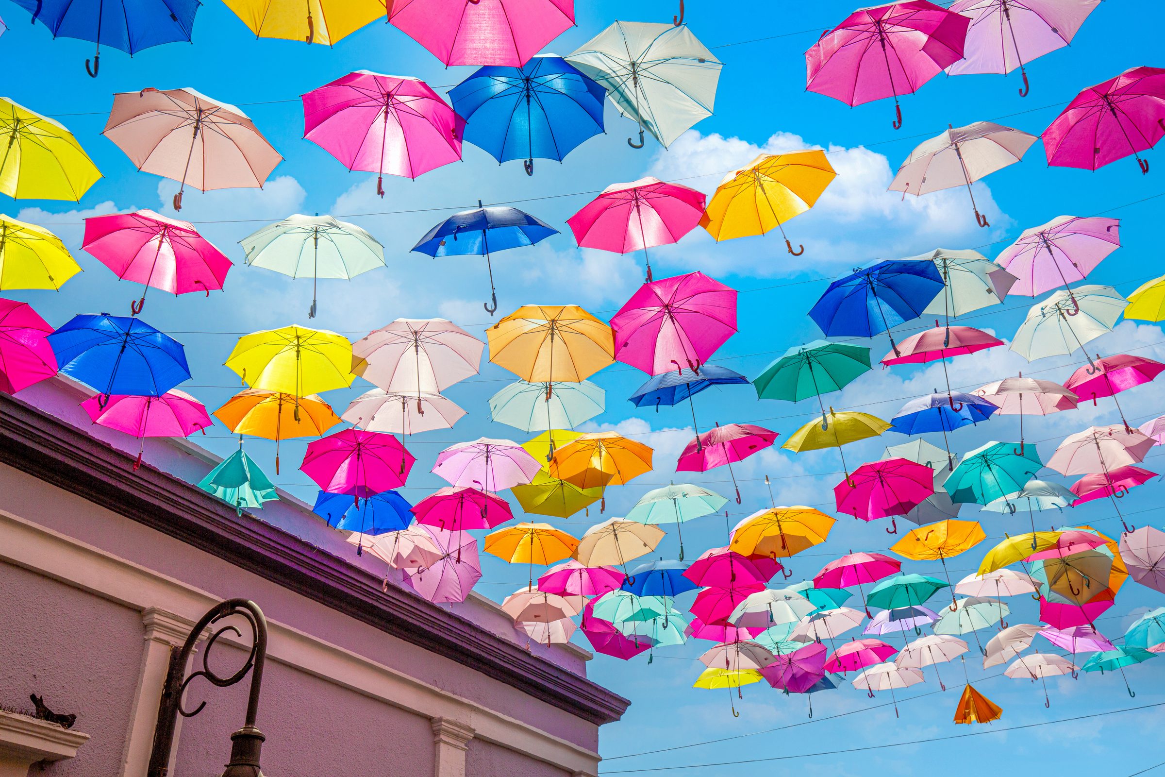 Bunte Sonnenschirme, die über einer sonnigen Gasse hängen