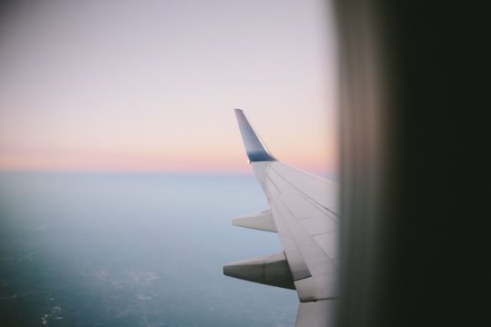 Blick aus einem Flugzeugfenster auf die Tragfläche bei Sonnenuntergang