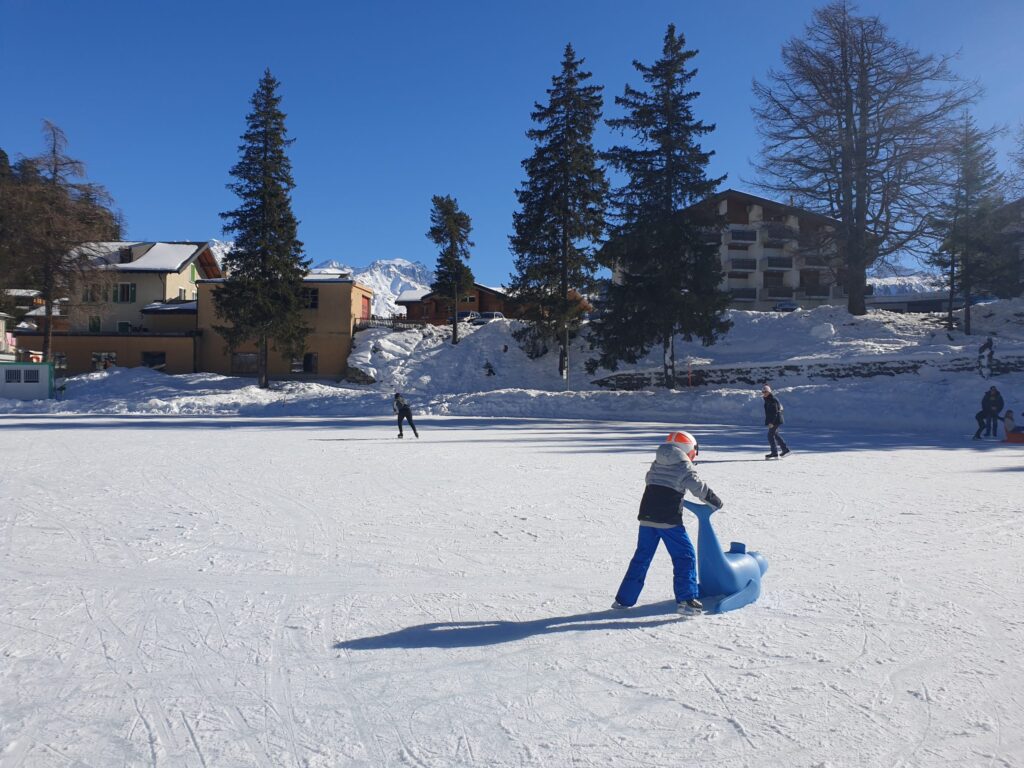 Patineurs sur le lac gelé de Champex, entouré de montagnes enneigées.